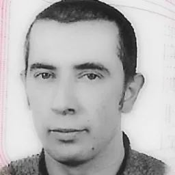 Czarno-białe zdjęcie portretowe mężczyzny o krótkich, ciemnych włosach, skierowanego lekko w lewo, z neutralnym wyrazem twarzy i widocznymi drobnymi zmarszczkami wokół oczu.