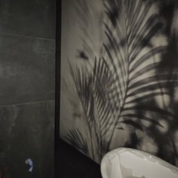 USŁUGI REMONTOWO WYKOŃCZENIOWE MARCIN LEWANDOWSKI - Nowoczesna łazienka z ciemnymi płytkami i fototapetą z motywem roślinnym, widoczna wanna owinięta folią ochronną.