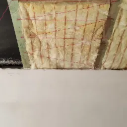 Izolacja termiczna stropu wełną mineralną, zabezpieczona sznurkiem, widoczne drewniane belki konstrukcyjne i fragment czarnej folii paroizolacyjnej, dolna część kadru wypełniona białą ścianą.