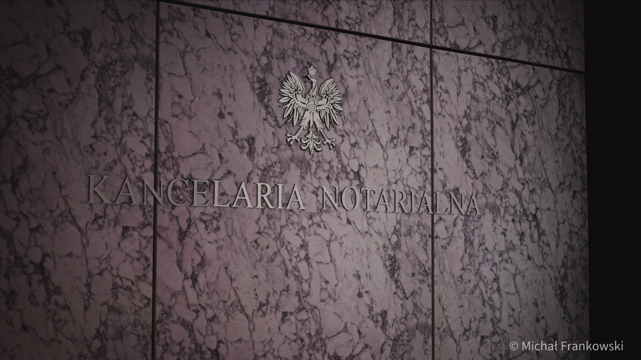 Elegancka marmurowa ściana z napisem 'Kancelaria Notarialna' i godłem Polski w srebrnym kolorze.