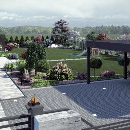 Pracownia Zieleni Konrad Zając - Nowoczesny ogród z podjazdem z kostki, zielonym trawnikiem, rabatami kwiatowymi i placem zabaw w tle. Widok z perspektywy.