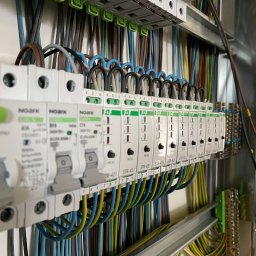 MAT-KAS Mateusz Kasperkiewicz - Rozdzielnica elektryczna z zamontowanymi ogranicznikami przepięć Noark STR-421, z podłączonymi przewodami w różnych kolorach. Widok z boku, oświetlenie naturalne.