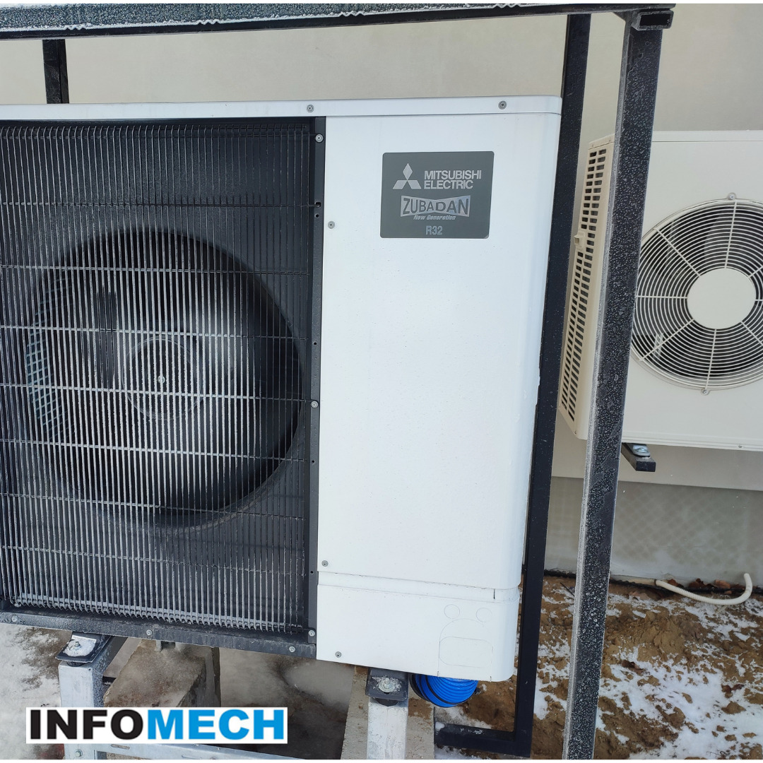 Dwie jednostki zewnętrzne, w tym jedna Mitsubishi Zubadan R32, zamontowane na metalowej konstrukcji na zewnątrz budynku, widoczne ślady śniegu na ziemi.