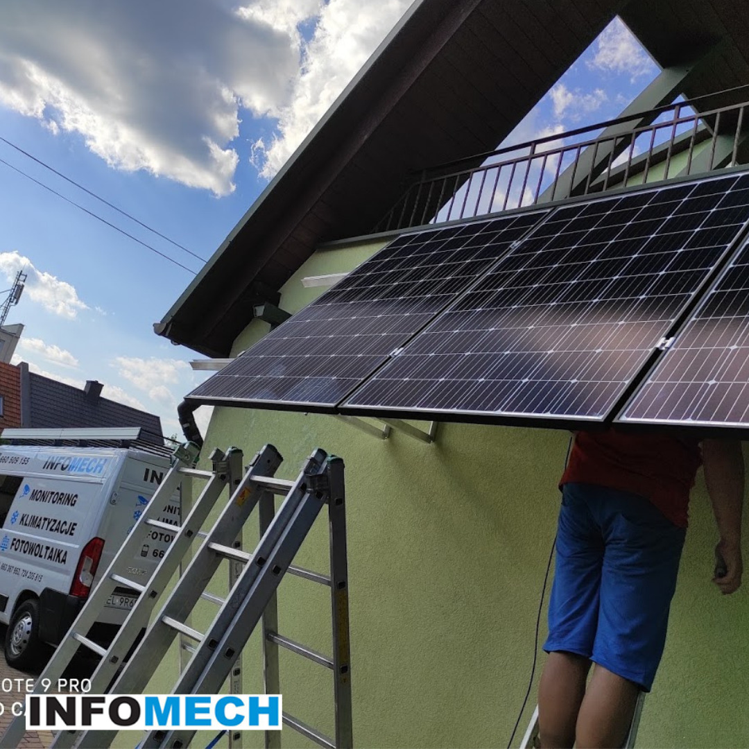 Montaż paneli słonecznych na ścianie domu, widoczne drabiny i fragment sylwetki instalatora, w tle firmowy bus z napisem 'Fotowoltaika'.