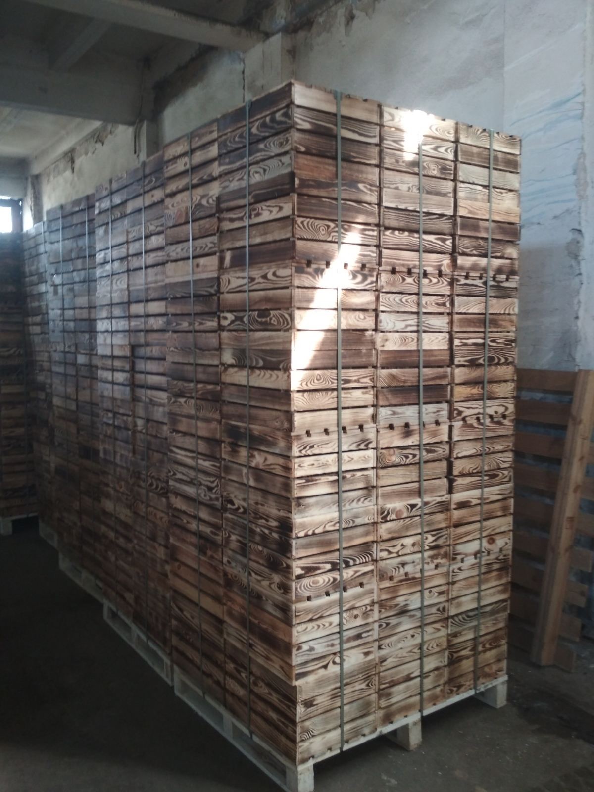 Stosy sprasowanego pelletu drzewnego ułożone na paletach w magazynie, zabezpieczone taśmą.