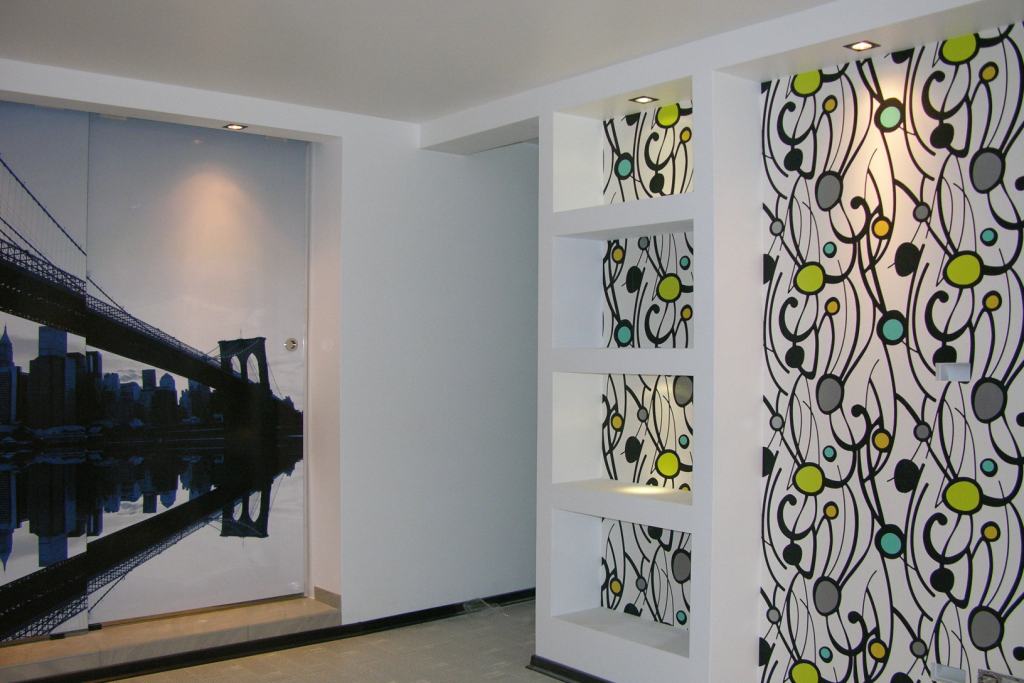 Wykończone wnętrze z fototapetą przedstawiającą most i panoramę miasta oraz ścianą z wnękami i dekoracyjnym wzorem.
