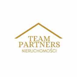Złote logo firmy Team Partners Nieruchomości z symbolem dachu na białym tle.