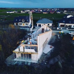 Paweł Mejza BUDOWNICTWO - Budowa domu jednorodzinnego z betonu komórkowego, widok z drona na fundamenty i ściany parteru, pompa do betonu w akcji, otoczenie: zabudowa jednorodzinna i pola.