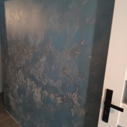 ROM Sławomir - Dekoracyjna ściana w odcieniach błękitu i szarości z efektem chmur, widoczna obok białych drzwi z czarną klamką. Unikalna faktura i wzór na ścianie.