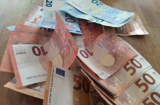 Stos banknotów euro o nominałach 10, 20 i 50 na drewnianym blacie, ułożone w nieporządku, z widocznymi detalami zabezpieczeń.