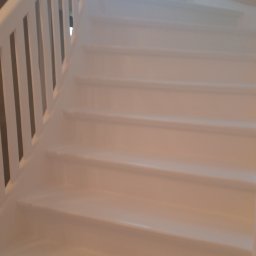 D.S.COLOR - Białe, drewniane schody kręcone z białą balustradą, oświetlone naturalnym światłem z okna, świeżo po odmalowaniu.