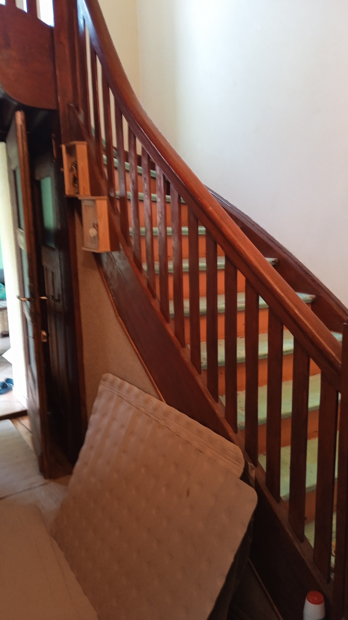 Klatka schodowa z drewnianą balustradą w trakcie prac remontowych, widoczne zabezpieczone schody i elementy konstrukcyjne.