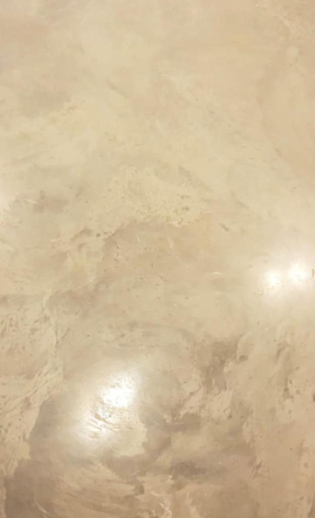 Beżowa, błyszcząca posadzka z efektem chmur i delikatnymi nierównościami, odbijająca światło.