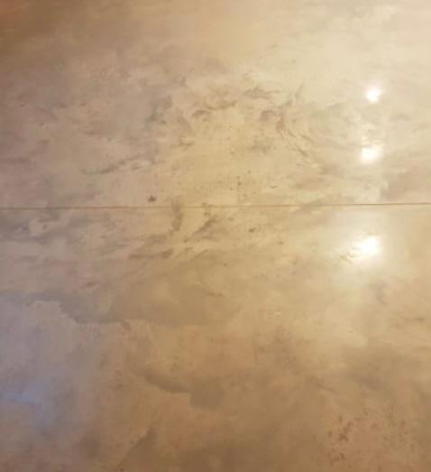 Jasnobrązowa, błyszcząca powierzchnia podłogi z efektem chmur, widoczne delikatne spoiny między płytami.