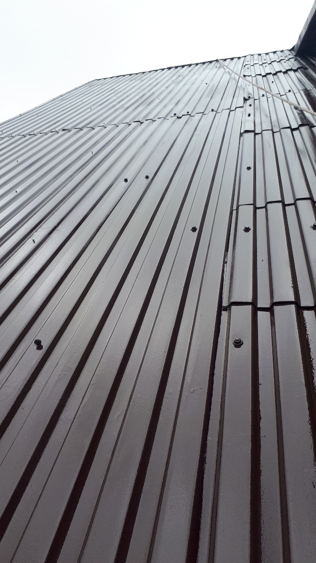 Nowy, brązowy dach z blachy trapezowej, mocowany na śruby, widok z dołu pod kątem.