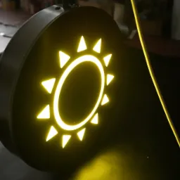 Podświetlany, okrągły szyld z motywem słońca wykonany z żółtego neonu, umieszczony na ciemnym tle.