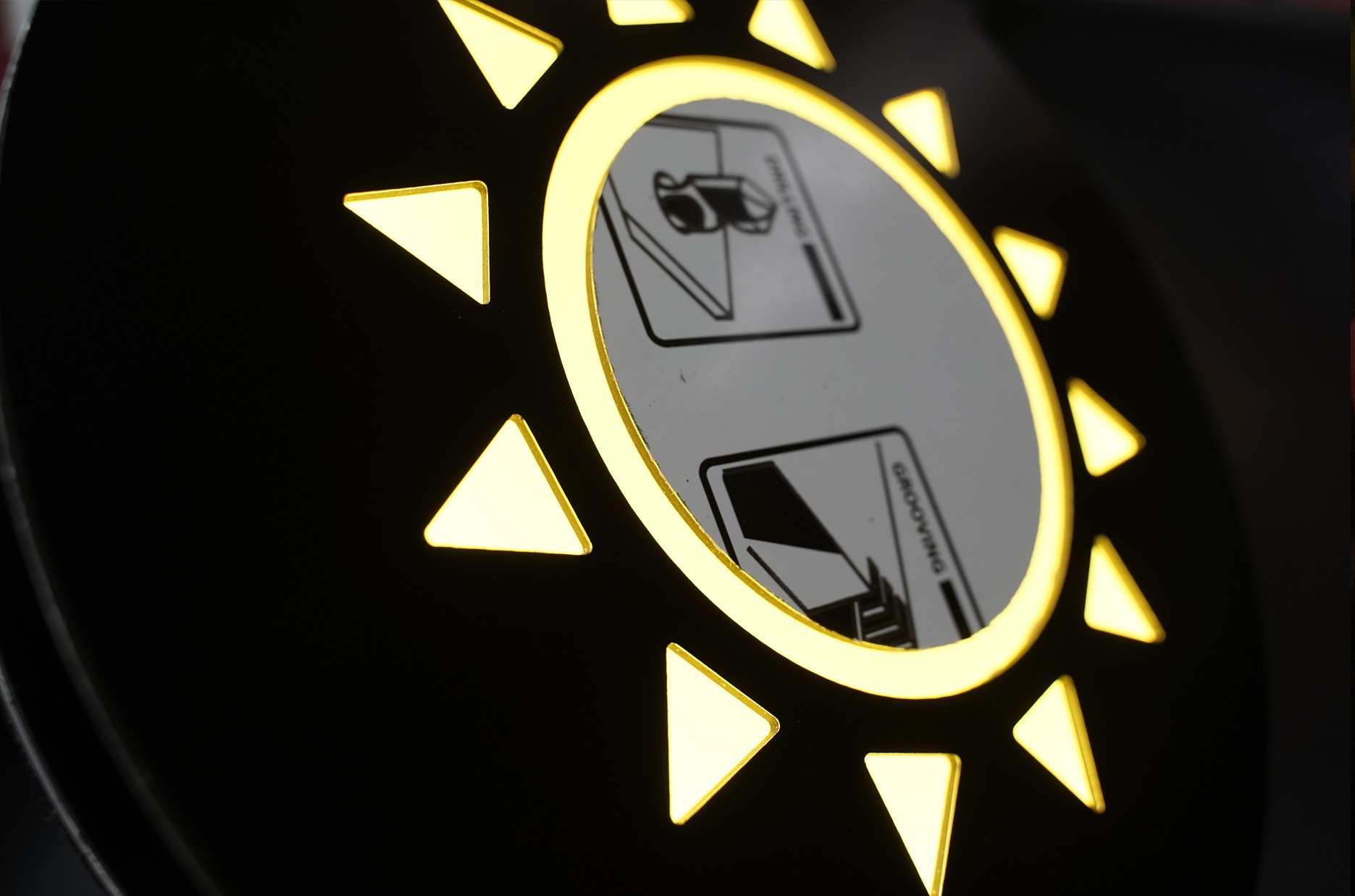 Podświetlany znak z ikonami przedstawiającymi proces drukowania i laminowania, otoczony trójkątnymi elementami w kształcie słońca.