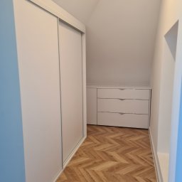 Meble na wymiar - Paweł Piórkowski - Biała szafa przesuwna i komoda z trzema szufladami wnękowe na poddaszu, parkiet w jodełkę. Funkcjonalne zagospodarowanie przestrzeni.