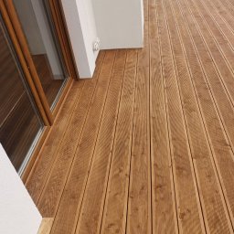 GregBud - Nowy taras z desek ryflowanych, ułożony przy białej ścianie budynku z oknem balkonowym, widok z góry pod kątem.