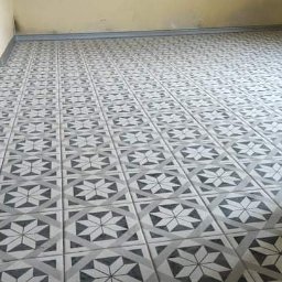 Super Mario Usługi Remontowo-Budowlane - Nowo ułożona podłoga z szarych i białych płytek ceramicznych z geometrycznym wzorem gwiazdy i rombu, widok z perspektywy drzwi.