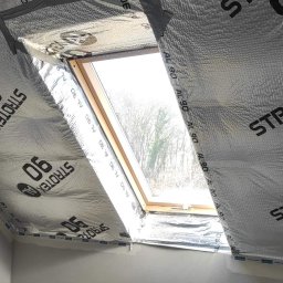 Super Mario Usługi Remontowo-Budowlane - Poddasze z oknem połaciowym w trakcie ocieplania, widoczna folia paroizolacyjna Strotex AL 90, zabezpieczająca konstrukcję przed wilgocią.