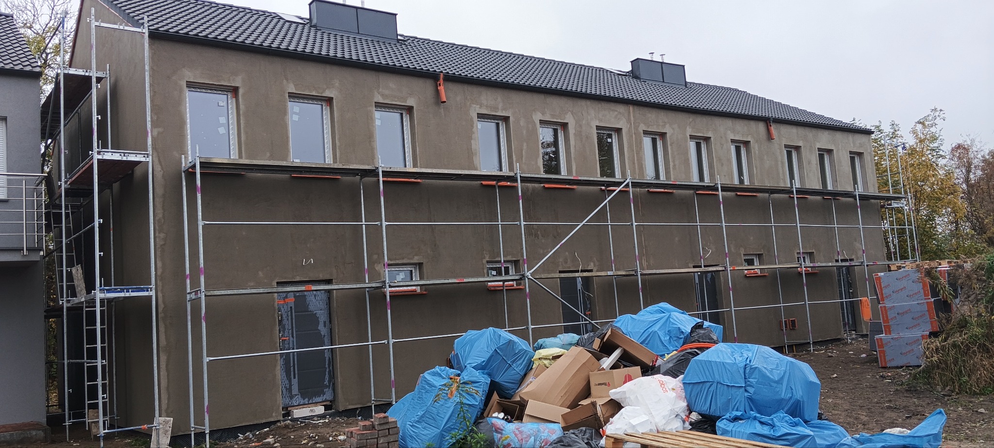 Budynek wielorodzinny w Wągrowcu w trakcie prac związanych z elewacją, widoczne rusztowania, ocieplenie oraz przygotowana powierzchnia pod tynk.
