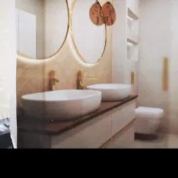 Nowoczesna łazienka z dwoma okrągłymi lustrami z podświetleniem LED, dwiema białymi umywalkami nablatowymi, złotą armaturą i toaletą w tle.