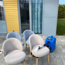 Zatoka Błysku Robert Mastela - Pranie krzeseł tapicerowanych na zewnątrz, z użyciem niebieskiego odkurzacza piorącego. Widoczne ślady po praniu na siedzisku krzesła.