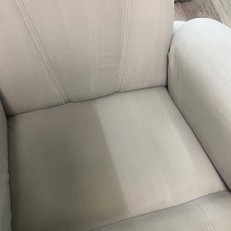 Zatoka Błysku Robert Mastela - Jasnoszary fotel z widoczną różnicą w czystości tapicerki po praniu. Połowa siedziska wyraźnie jaśniejsza i czystsza, ukazująca efekt usługi.