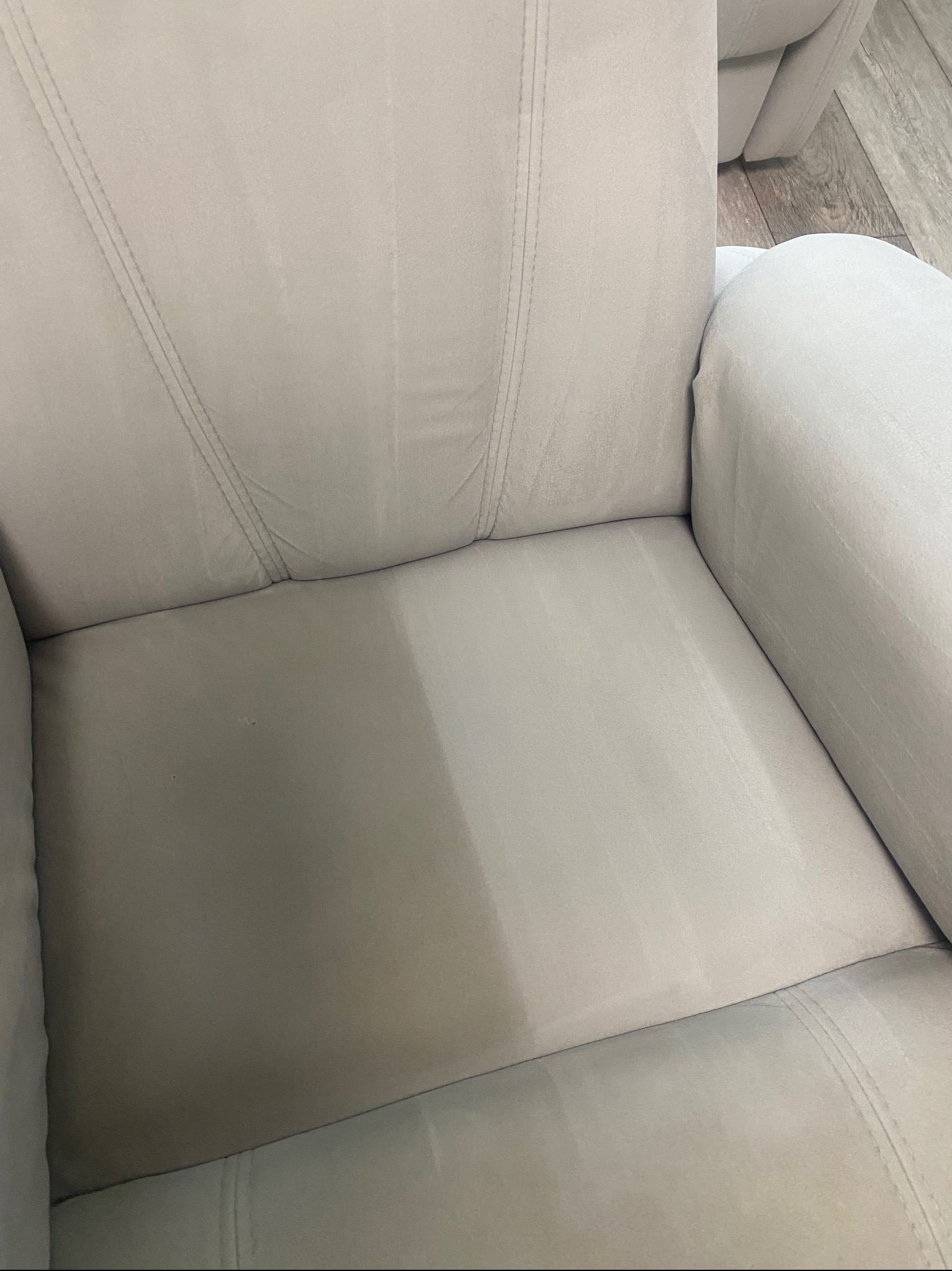 Jasnoszary fotel z widoczną różnicą w czystości tapicerki po praniu. Połowa siedziska wyraźnie jaśniejsza i czystsza, ukazująca efekt usługi.