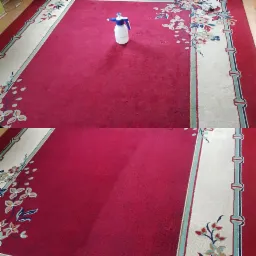 Czerwony dywan z kwiatowym wzorem, częściowo wyczyszczony, z widoczną różnicą w kolorze w Wałbrzychu. Na dywanie stoi biały spryskiwacz.