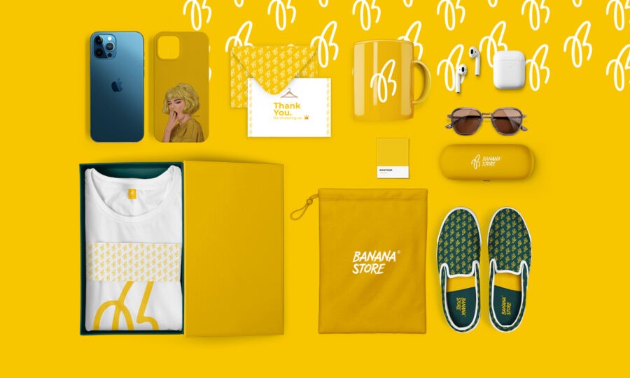 Zestaw produktów marki Banana Store na żółtym tle, zawierający telefon, etui, koszulkę, kubek, słuchawki, okulary, woreczek i buty, prezentowany przez firmę z Augustowa.