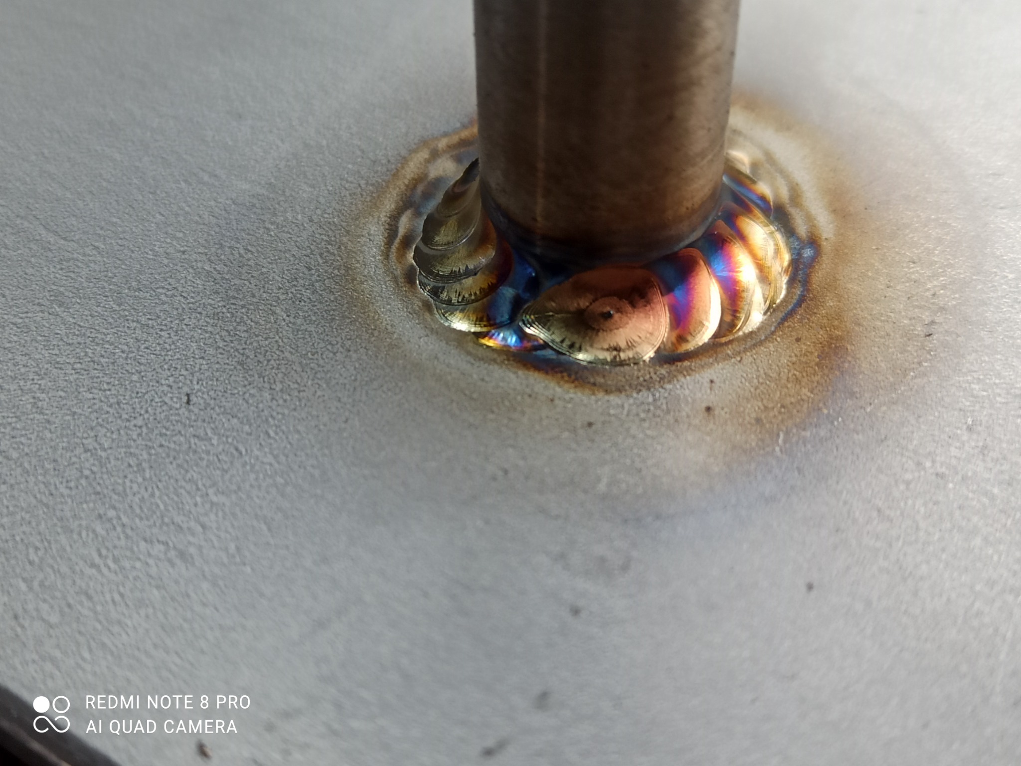 Spoina po spawaniu rury do płaskiej powierzchni, widoczne charakterystyczne kolory temperaturowe i ślady po procesie