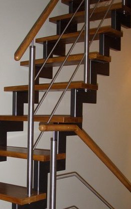 Nowoczesne schody drewniane z czarnymi wspornikami i metalowymi poręczami, widok z dołu.