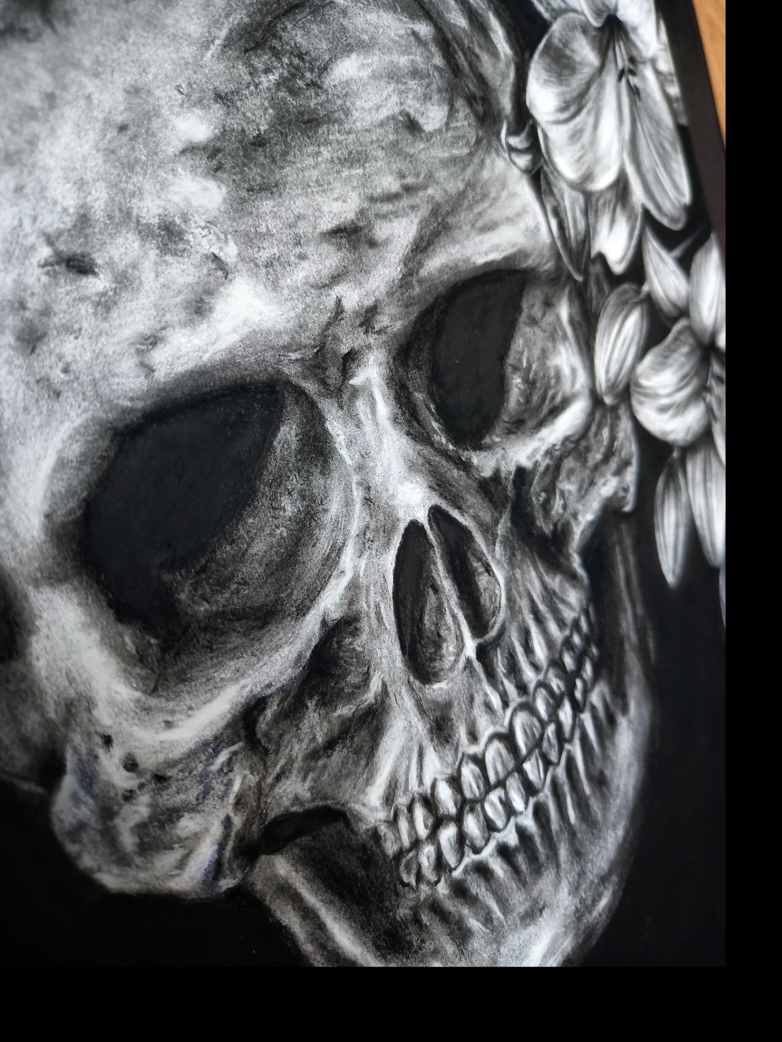 Czarno-biały rysunek węglem przedstawiający czaszkę ozdobioną kwiatami lilii, z wyraźnymi detalami cieniowania i tekstury.