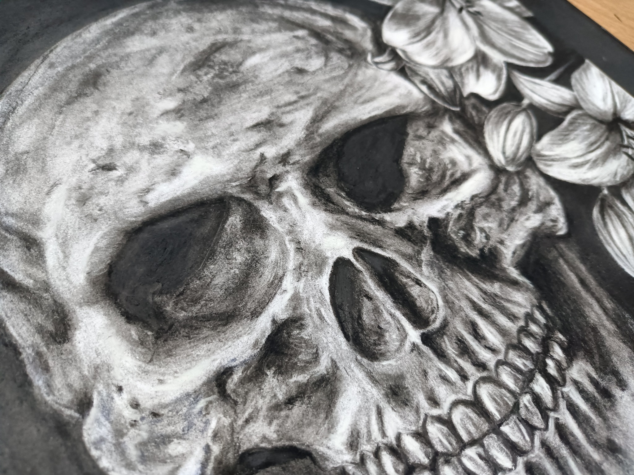 Szkic ołówkowy przedstawiający czaszkę ozdobioną kwiatami, wykonany z dbałością o detale cieniowania.