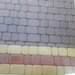 Ułożona kostka brukowa w odcieniach szarości, żółci i czerwieni, tworząca geometryczny wzór na powierzchni.