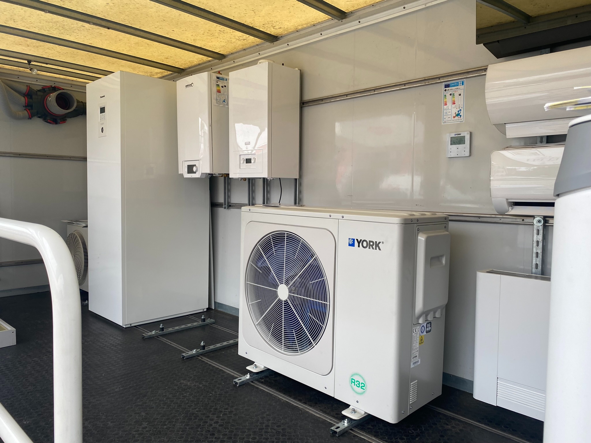 Wnętrze pojazdu z zainstalowanymi urządzeniami grzewczymi i klimatyzacyjnymi marki York, w tym pompy ciepła, kotły i klimatyzatory, zamontowane na metalowych szynach.