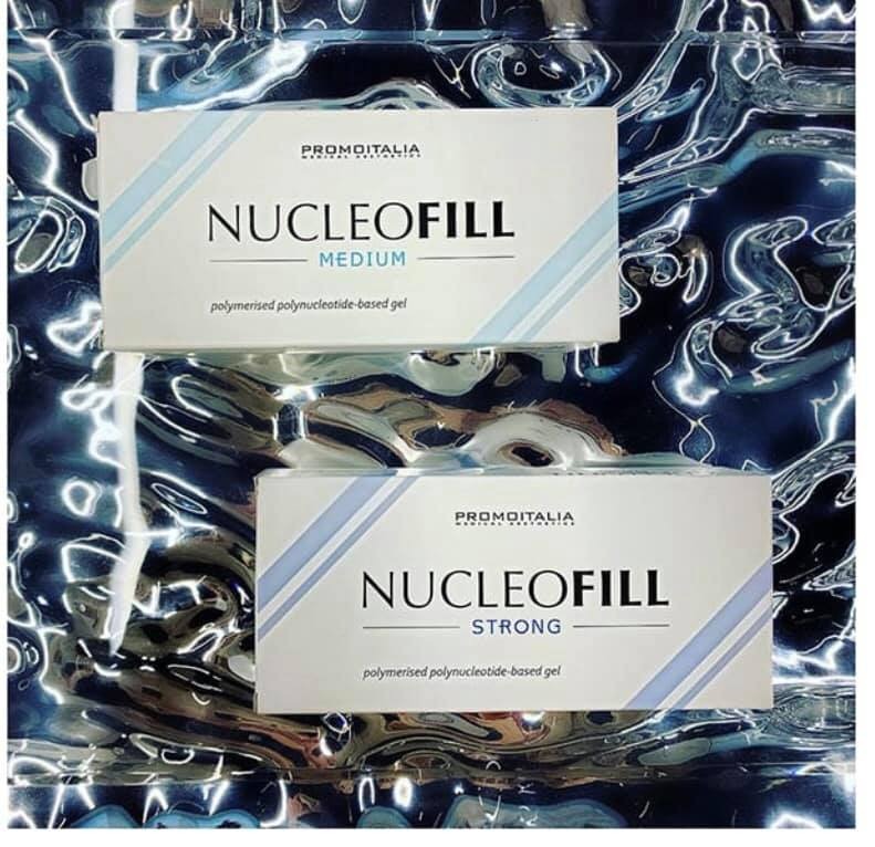 Dwa opakowania preparatu Nucleofill Medium i Strong firmy Promoitalia na abstrakcyjnym tle imitującym wodę.
