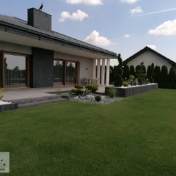 Ogród z tarasem otoczony podwyższanymi donicami.