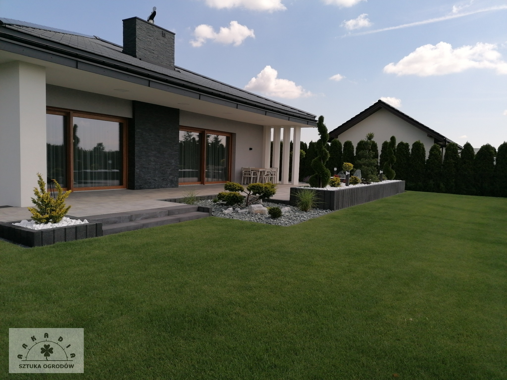 Ogród z tarasem otoczony podwyższanymi donicami.