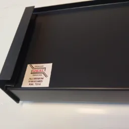 Ciemnoszary aluminiowy parapet z naklejoną etykietą producenta 'Ideal'