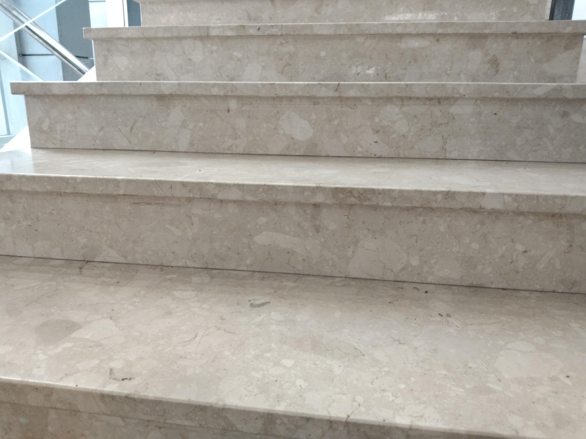 Schody wykończone jasnym konglomeratem z widocznym wzorem marmuru, zakończone zaokrąglonymi krawędziami.