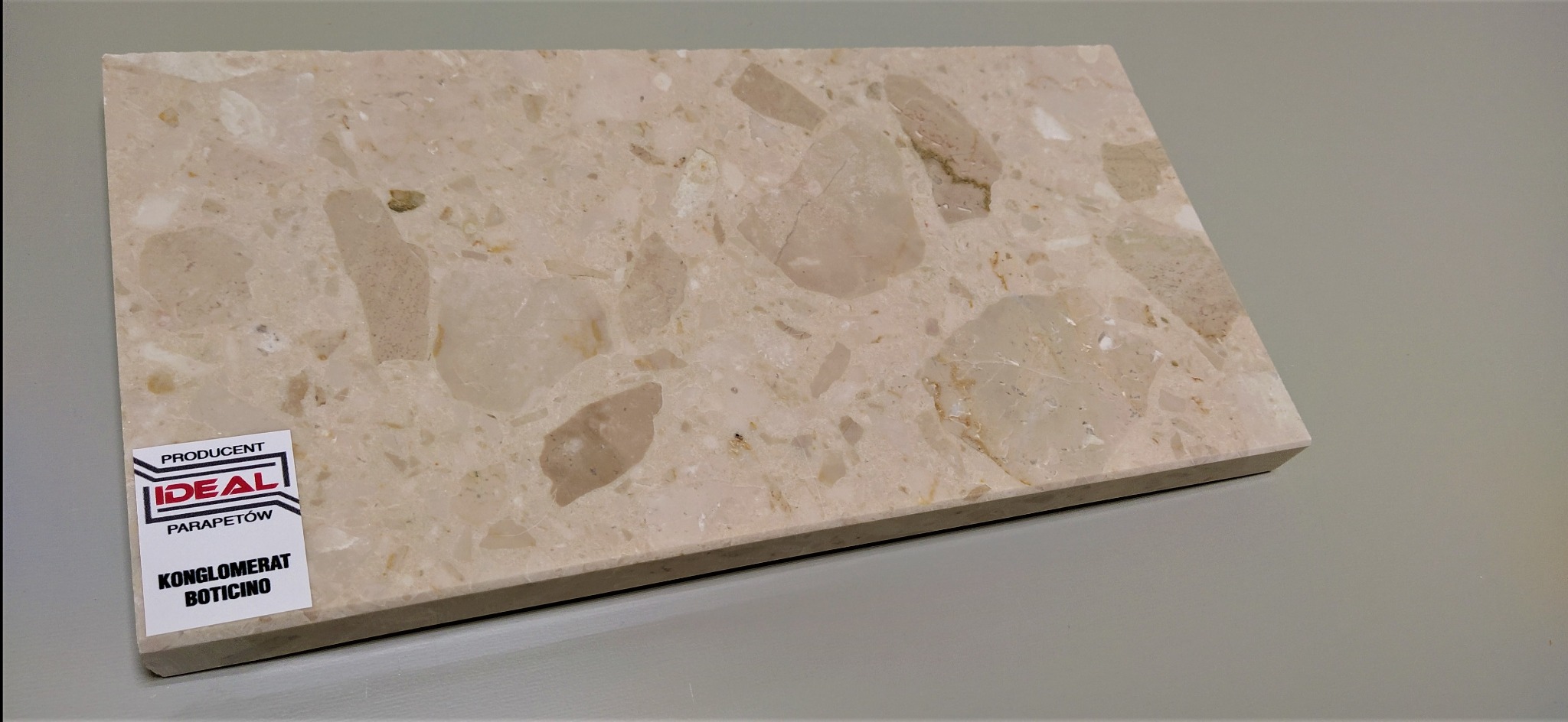 Próbka konglomeratu Boticino z naklejką producenta 'Ideal Parapetów' prezentująca strukturę i kolorystykę materiału.