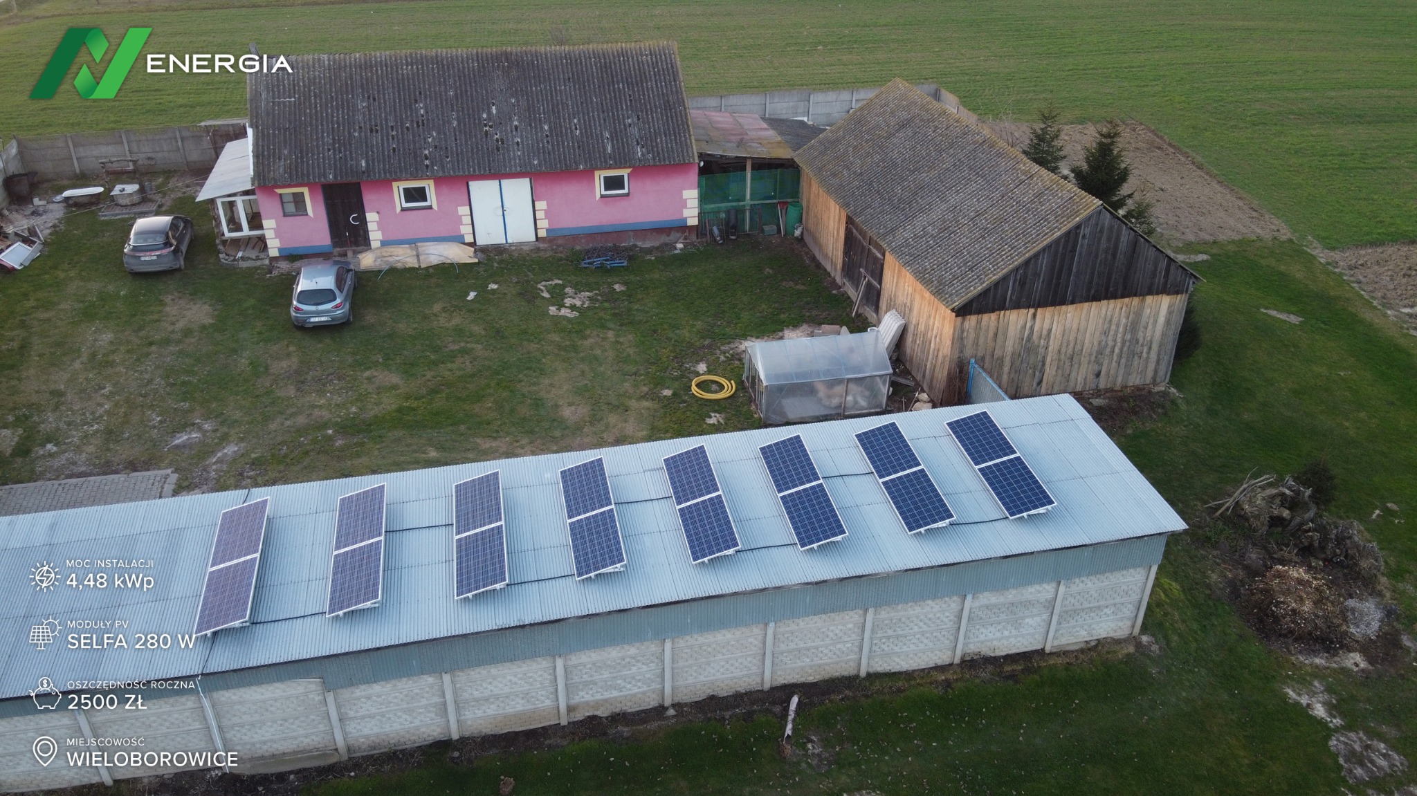 Instalacja fotowoltaiczna na dachu budynku gospodarczego w Wieloborowicach, widok z lotu ptaka, z informacjami o mocy instalacji 4.48 kWp i rocznych oszczędnościach 2500 zł, moduły PV Selfa 280W.