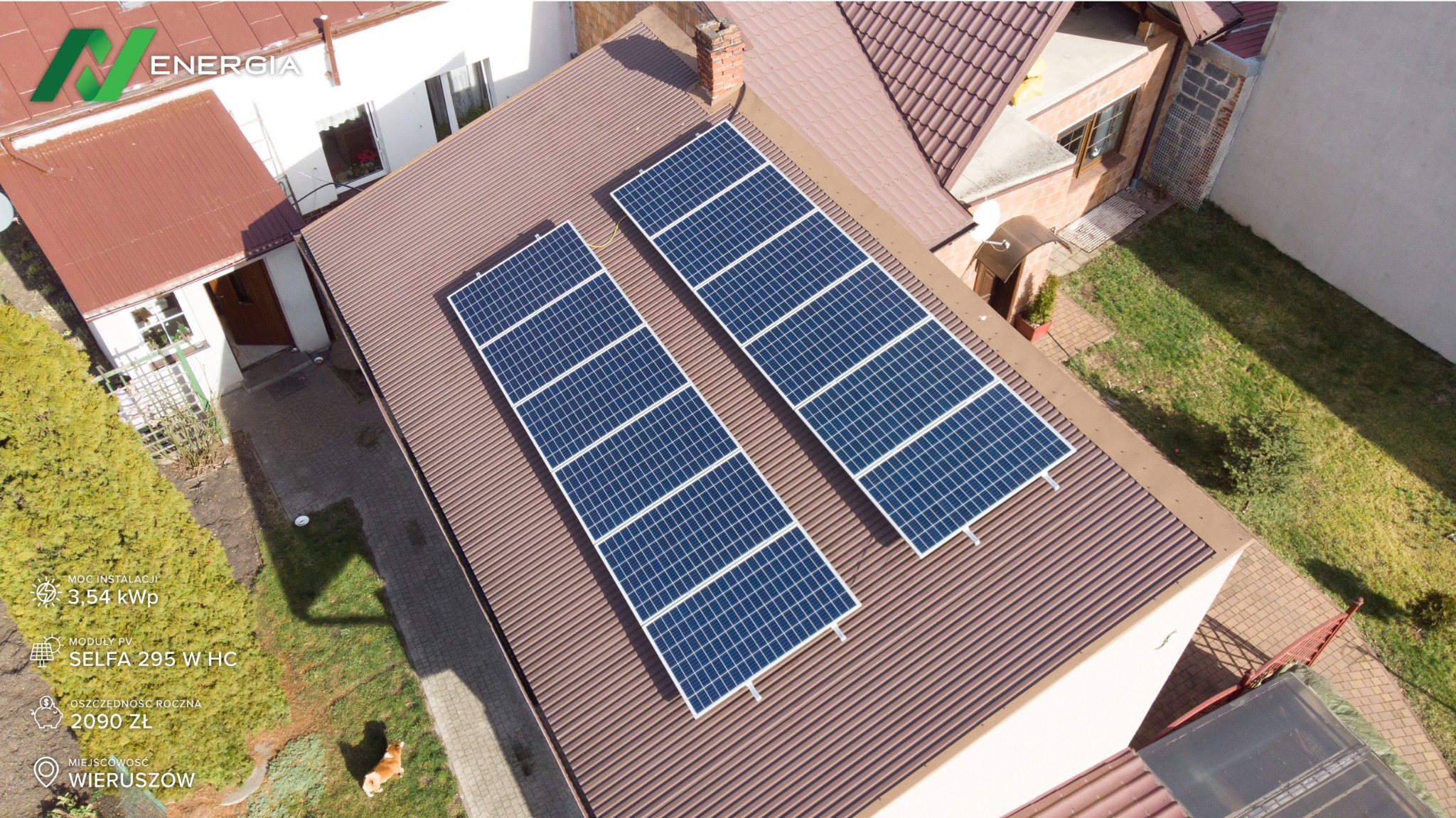 Widok z góry na brązowy dach domu z dwoma rzędami paneli słonecznych SELFA 295 W HC, instalacja 3,54 kWp, Wieruszów, roczna oszczędność 2090 zł, w tle widoczny ogród i budynki.