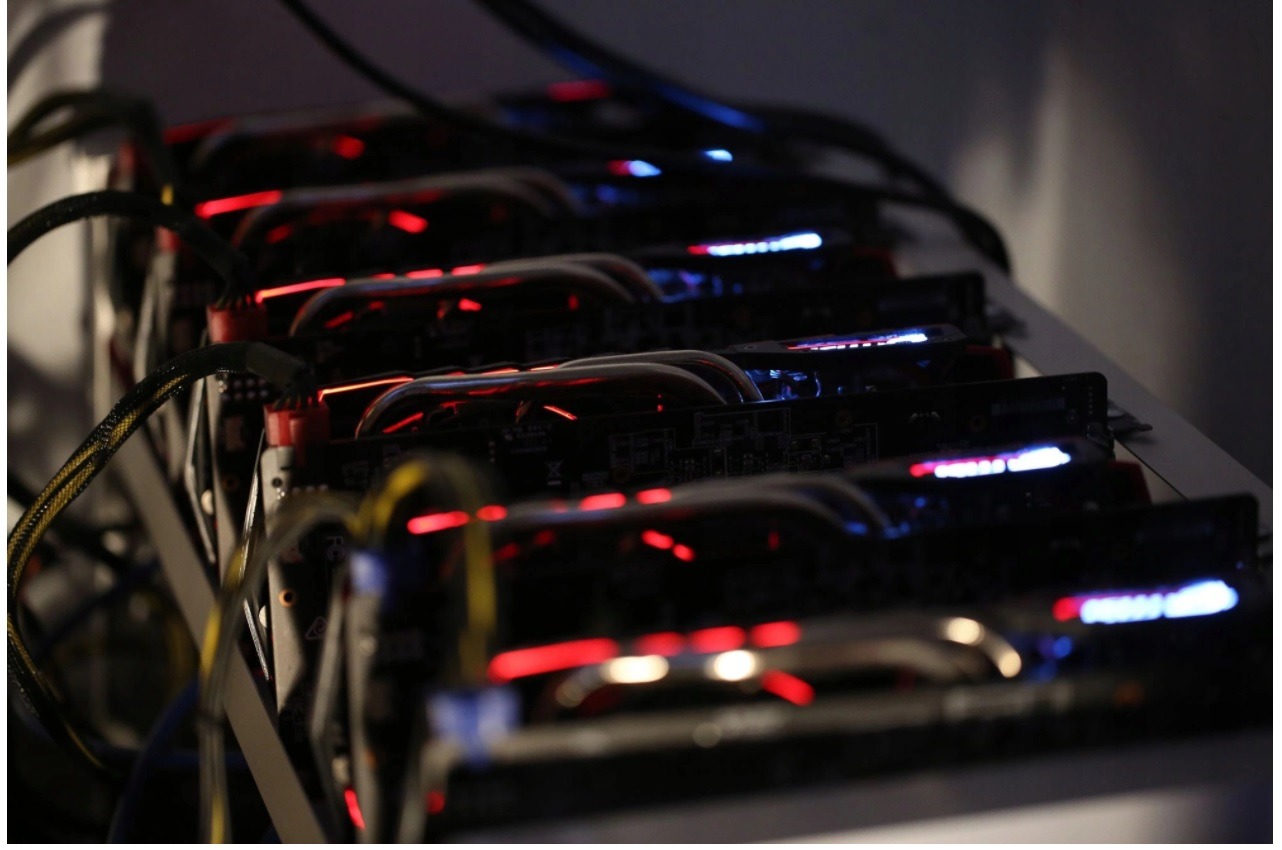 Rząd kart graficznych z czerwonym i niebieskim podświetleniem, połączonych kablami, prawdopodobnie farma kryptowalut.
