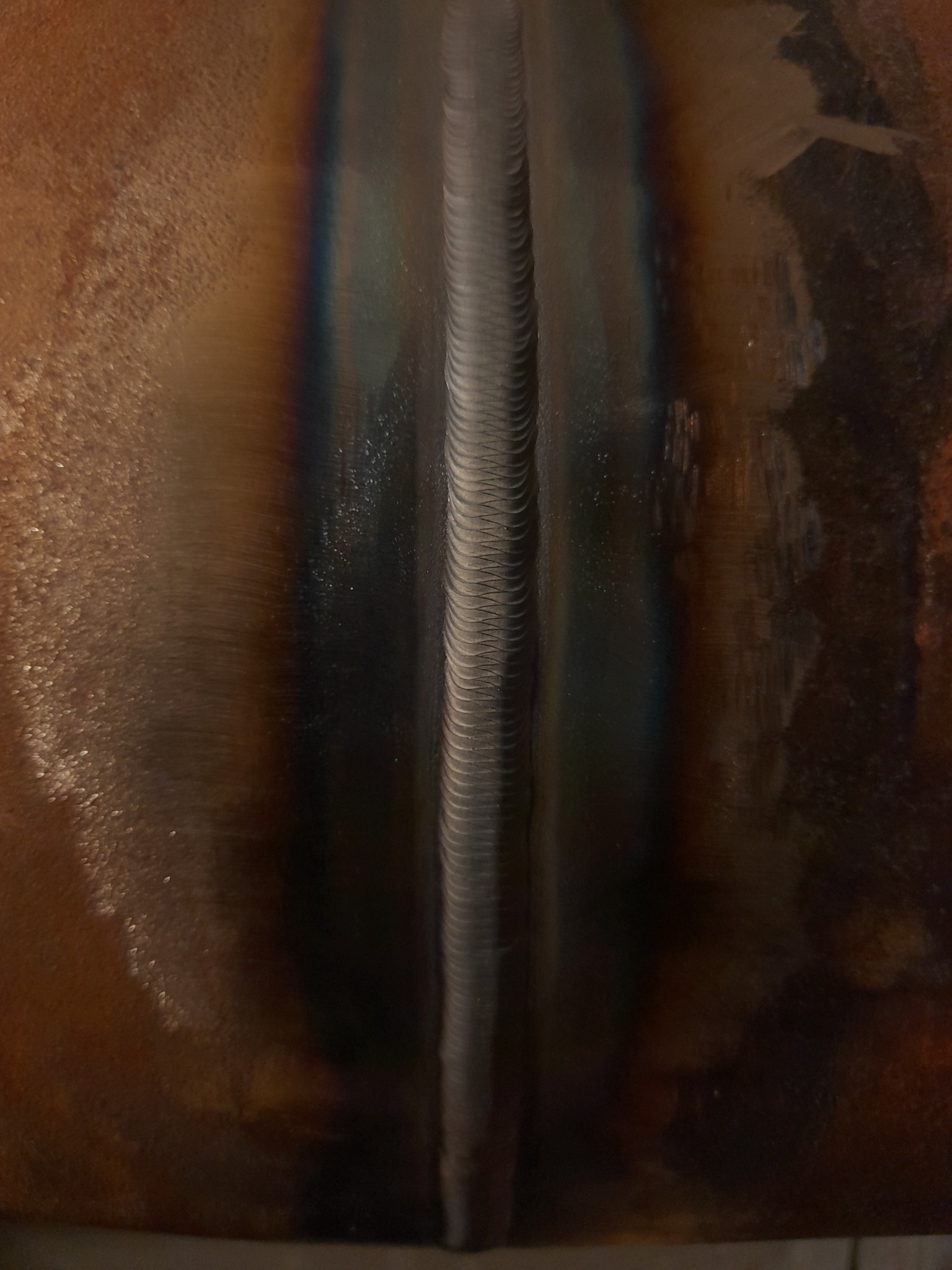 Detal zdjęcia świeżo wykonanego spoiny na rurze, widoczne ślady ciepła i charakterystyczne zabarwienie metalu.