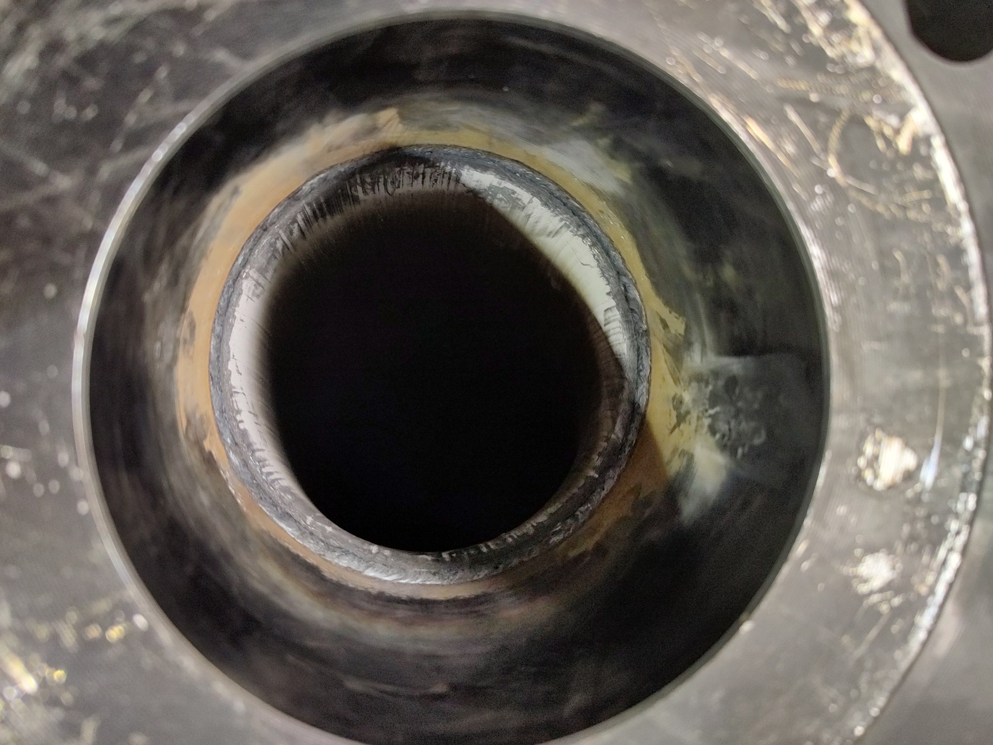 Wewnętrzna strona spawanej rury ze stali nierdzewnej, widoczne ślady po spawaniu i obróbce, ciemne wnętrze.