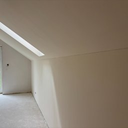 RN-BUD SERHII ZOSYK - Poddasze po remoncie: gładkie, jasne ściany w odcieniach beżu, okno dachowe i widok na zieleń za oknem. Minimalistyczne wykończenie wnętrza.